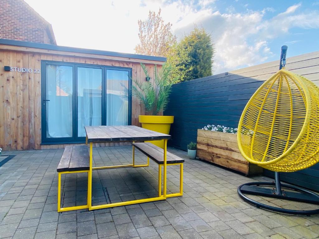 a picnic table and a yellow swing on a patio at Studio 22 in Harrogate
