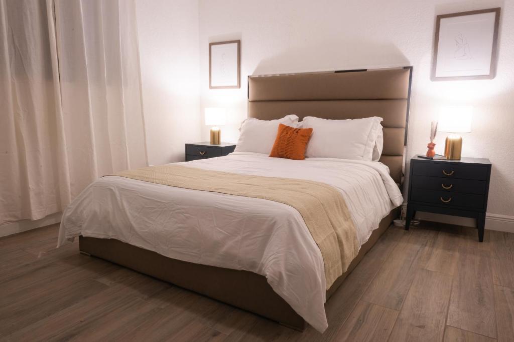 ノースマイアミビーチにあるNew Star Suite Twoのベッドルーム1室(白いシーツとオレンジの枕が備わる大型ベッド1台付)