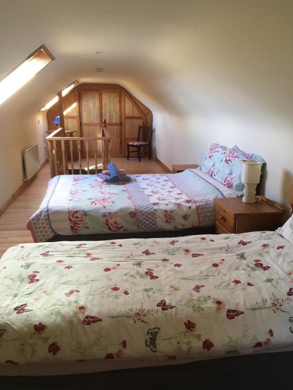 a bedroom with two beds with flowers on the sheets at Kate’s Cottage 