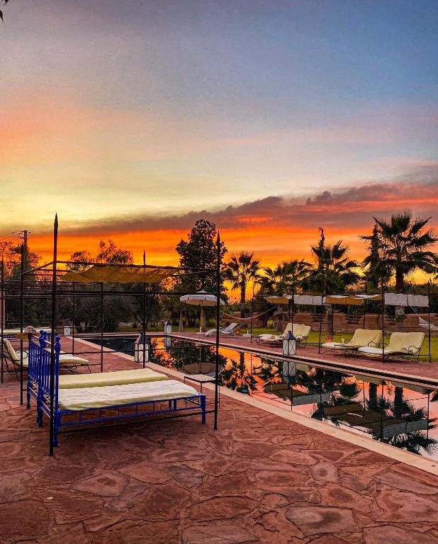 a park with a bed and a pool at sunset at Jnane Allia in Douar Soukkane