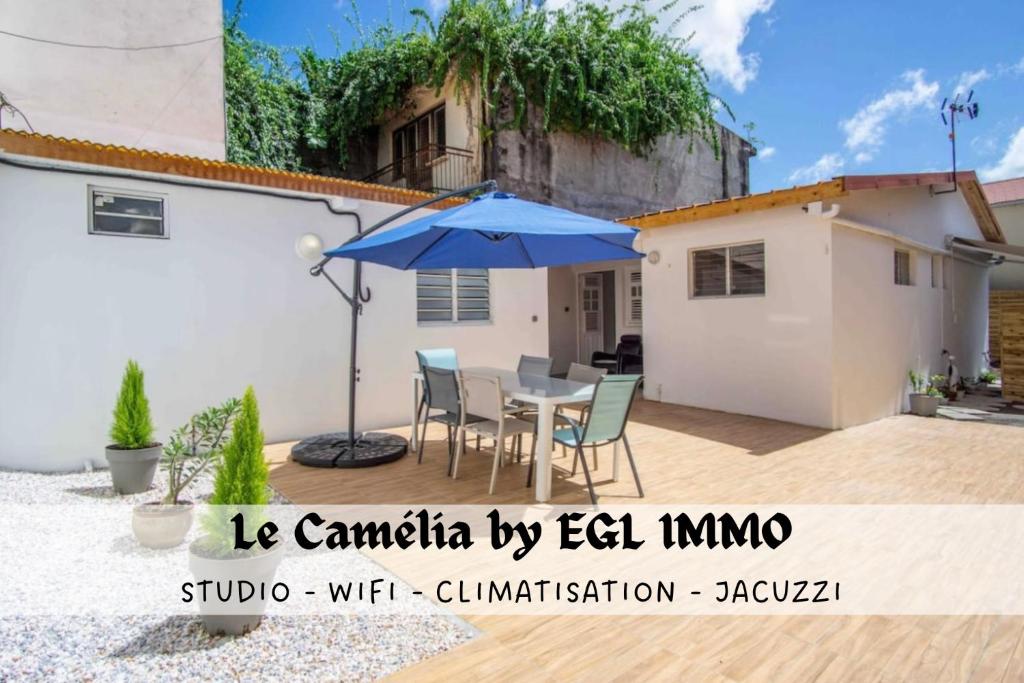 een patio met een tafel en een parasol bij Le Camélia - Gîte "Terre et Truffes" in Le Lamentin