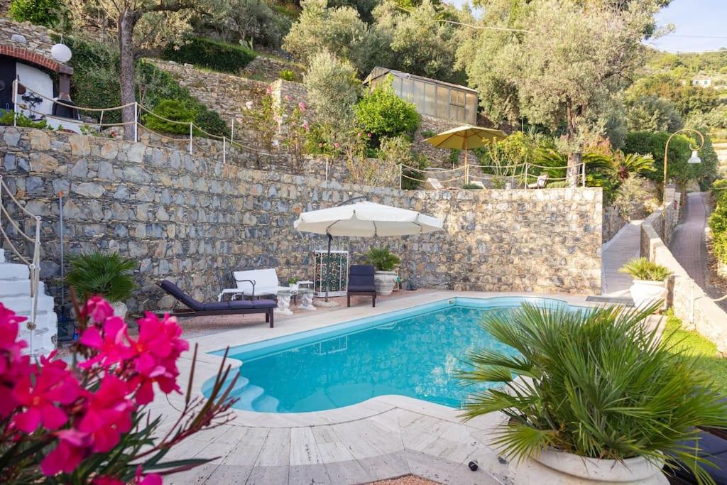 una piscina con sombrilla y algunas flores en Sea South front property1/2acre.Gardens pool hydro, en Pieve Ligure