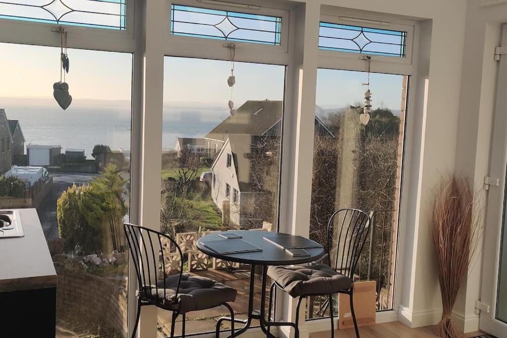 a table and chairs in a room with a large window at KINGHORN - Private room, ensuite & sunroom with Fab views in Kinghorn