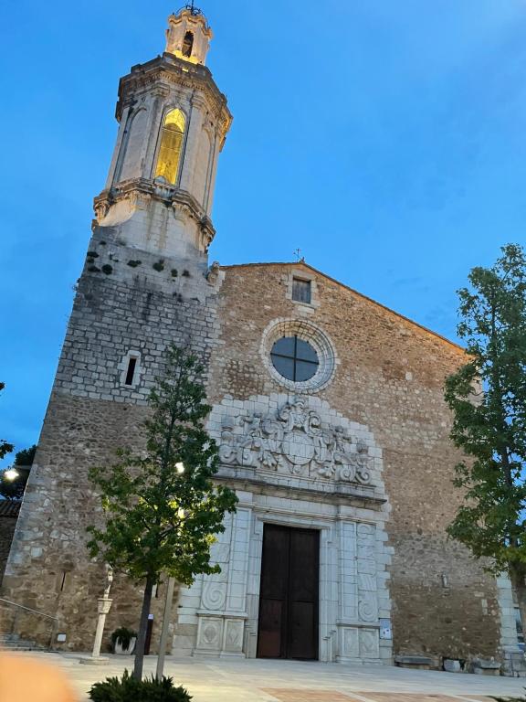 a church with a tower with a clock on it at Empordà Country House in Borrassá