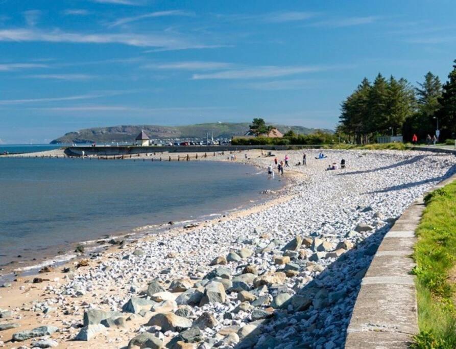 a beach with rocks and people on the water at Coetmor Cottage in Llanfairfechan