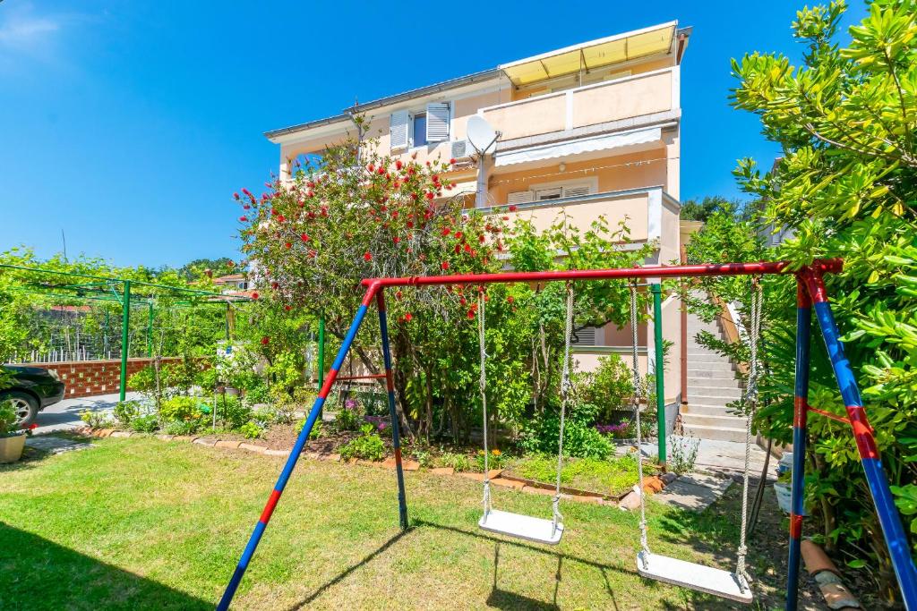 a swing in a yard with a house at Apartments Marija I in Lopar