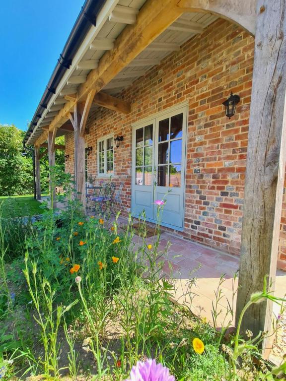 a brick house with a blue door and flowers at Dragonfly cottage in Christchurch