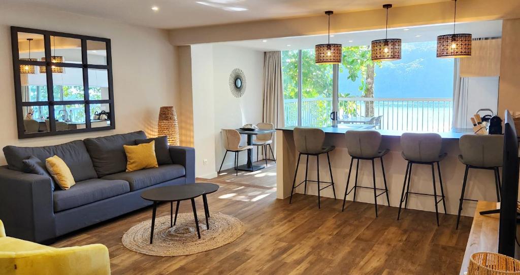 ein Wohnzimmer mit einem Sofa und einer Bar mit Hockern in der Unterkunft Pacific Suite in Arue