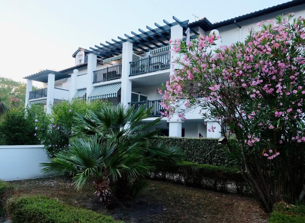 un edificio blanco con flores rosas delante en Appartement dans résidence au calme, en Bayona