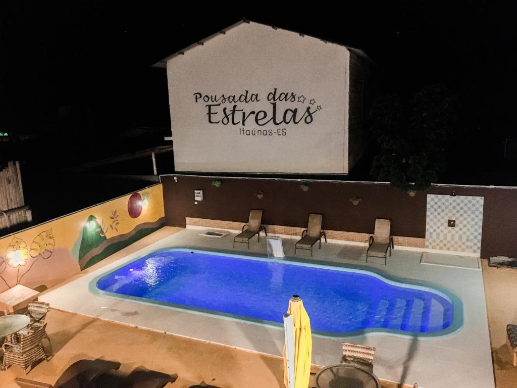 a large swimming pool with chairs next to a box at Pousada das Estrelas in Itaúnas