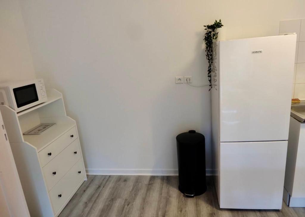 a room with a refrigerator and a dresser with a microwave at Appartement dans résidence au calme in Bayonne