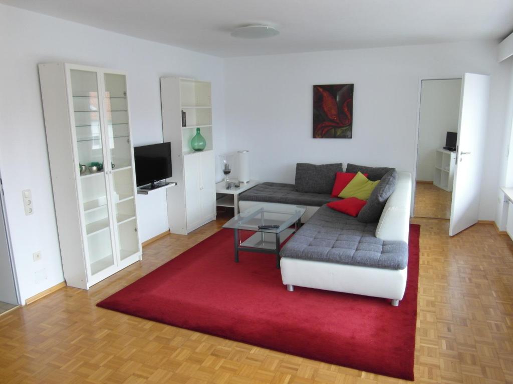 un soggiorno con divano e tappeto rosso di Augusta-Refugium a Augusta (Augsburg)