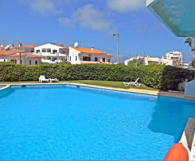 a large blue swimming pool with two chairs next to a house at Alvor Suite Apartment in Alvor