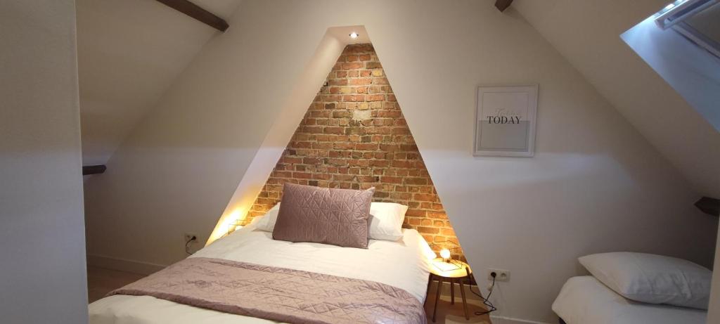 a bed in a room with a brick wall at Maison Rose Plopsaland in De Panne