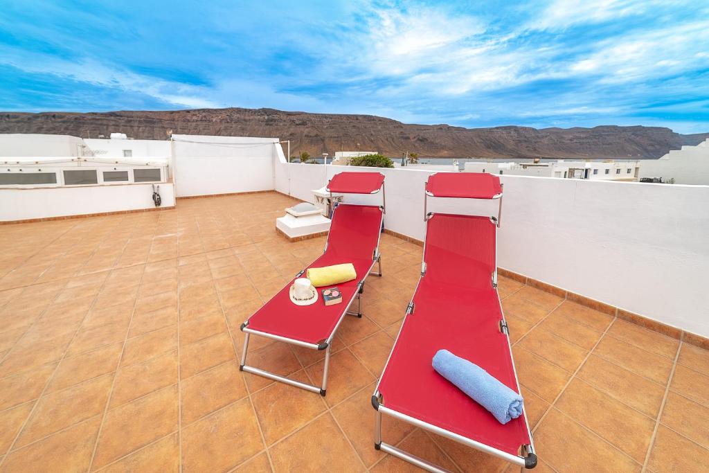 eine Terrasse mit zwei roten Stühlen und einem Avisorvisor in der Unterkunft Casa Vlaorda by HH in Caleta de Sebo