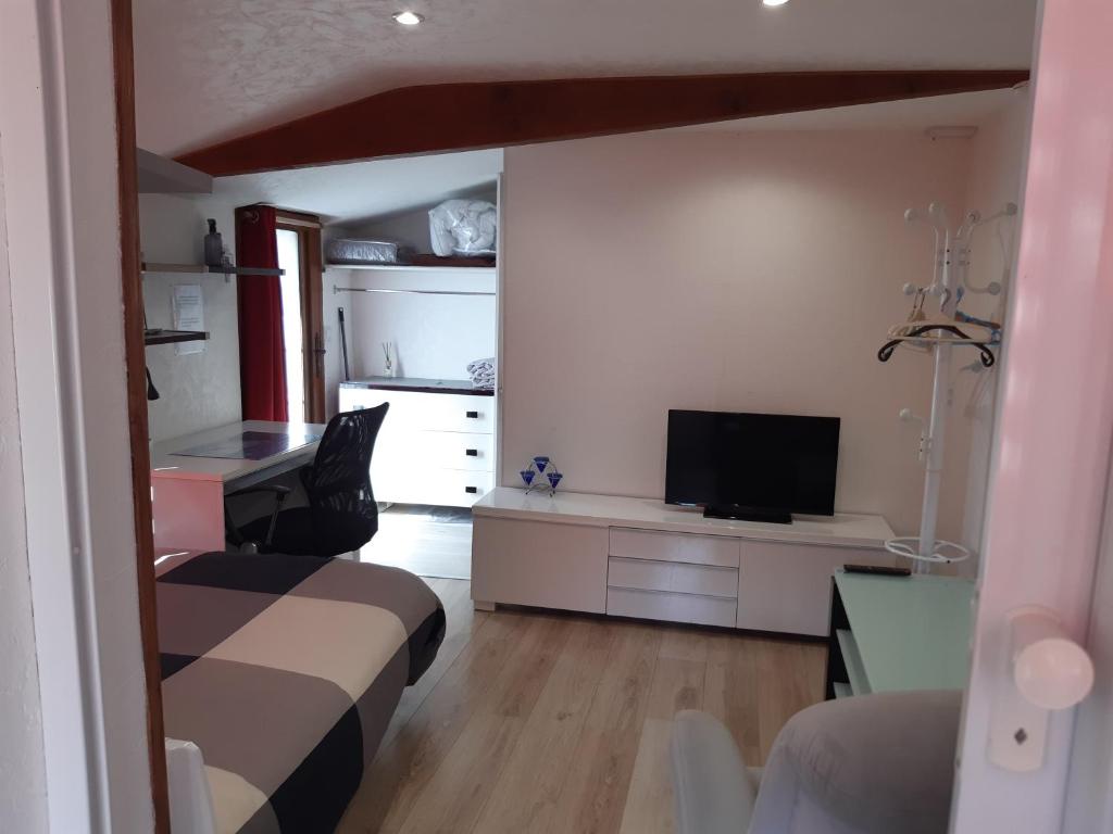 Zimmer mit einem Bett und einem Schreibtisch mit einem TV in der Unterkunft Studio indépendant in Saint-Illiers-la-Ville