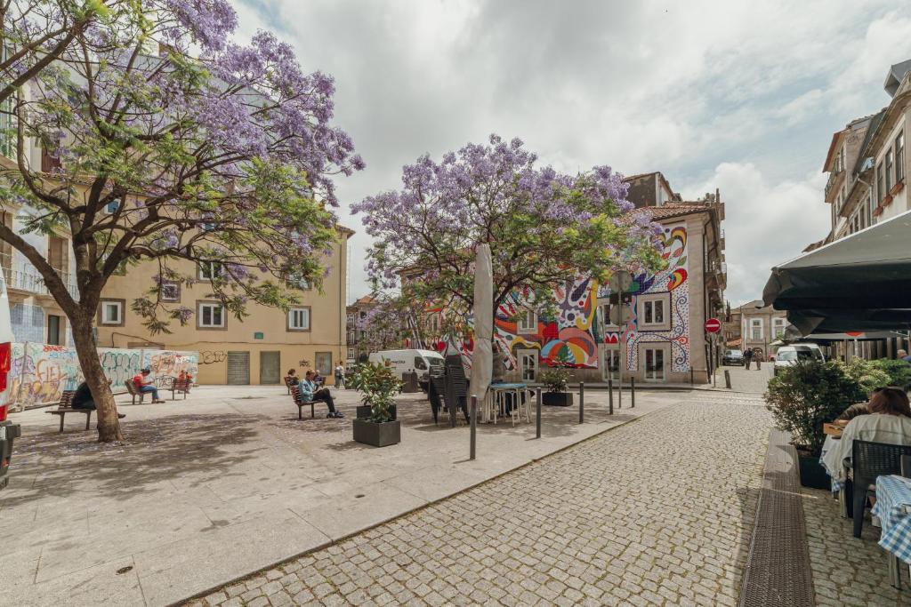 a city street with trees with purple flowers at OPORTO GUEST Moinho de Vento Studios in Porto