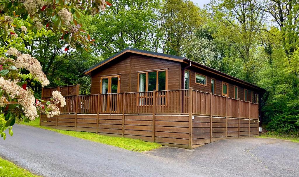 une cabane en bois avec une clôture devant elle dans l'établissement Charming Copse Corner Cabin in Devon's Countryside, à Chudleigh