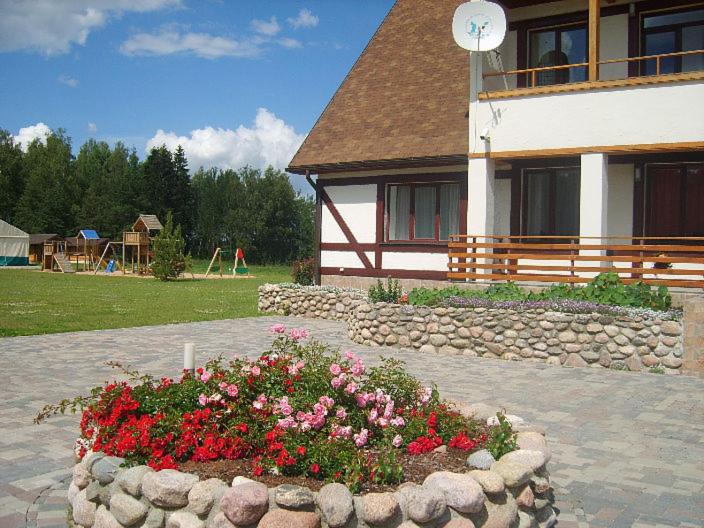 a flower garden in front of a building at Viesu Nams Vecupe in Birzgale