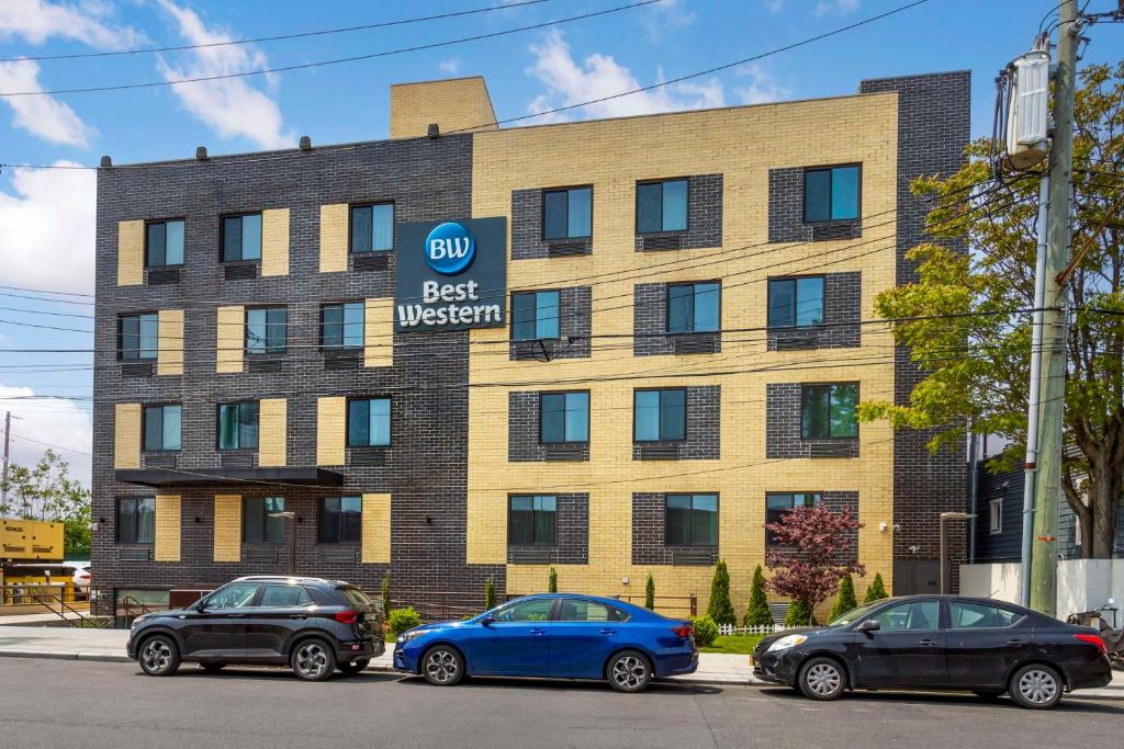 un bâtiment avec trois voitures garées devant lui dans l'établissement Best Western Brooklyn-Coney Island Inn, à Brooklyn