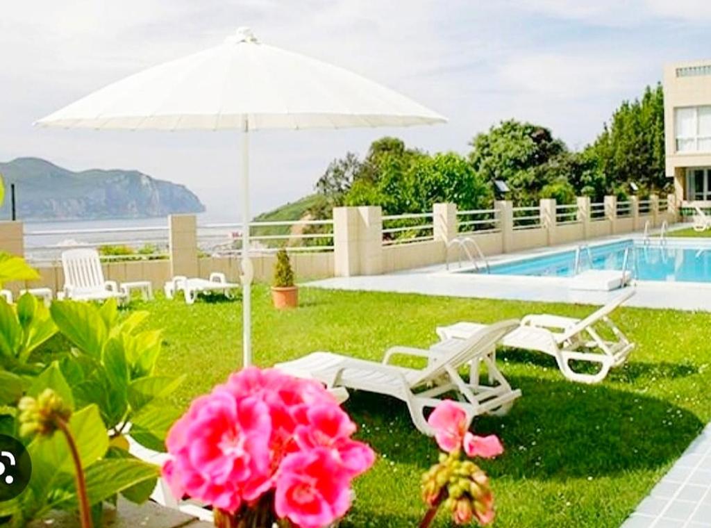 a patio with chairs and an umbrella and a pool at Hotel Miramar Laredo in Laredo