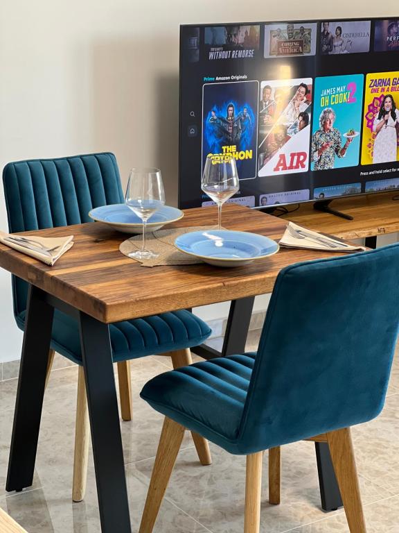 una mesa de madera con 2 copas de vino y sillas azules en Apartment Summer Night, en Preko