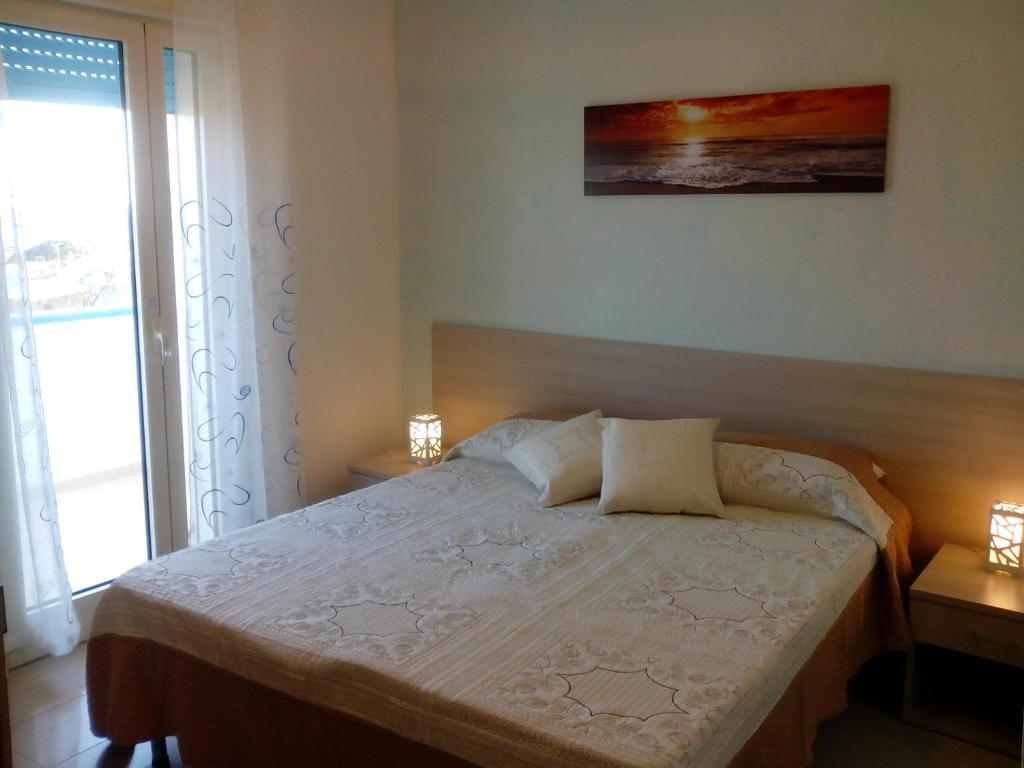 トッリチェッラにあるB&B Trullo di Mareのベッドルーム1室(ランプ2つ、窓付)