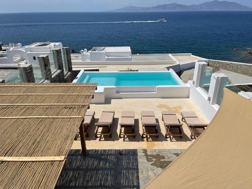 a swimming pool on a building with chairs and the ocean at Villa Sunset Aura - Amazing Sea & Sunset View in Klouvas