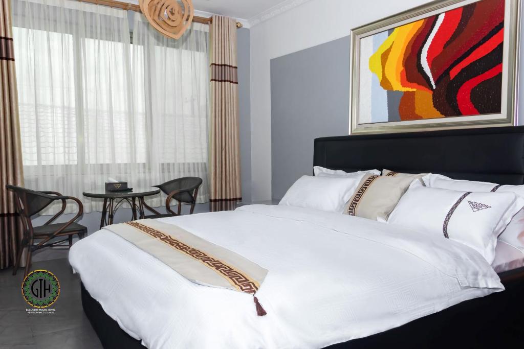 a bedroom with a large white bed and a table at Gullivers Travel Hotel in Apenkwa