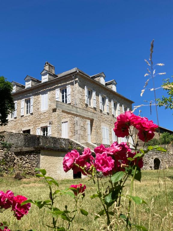 an old stone building with pink flowers in the foreground at Maison Balmelle - Maison d'hôtes de Caractère in Gramat
