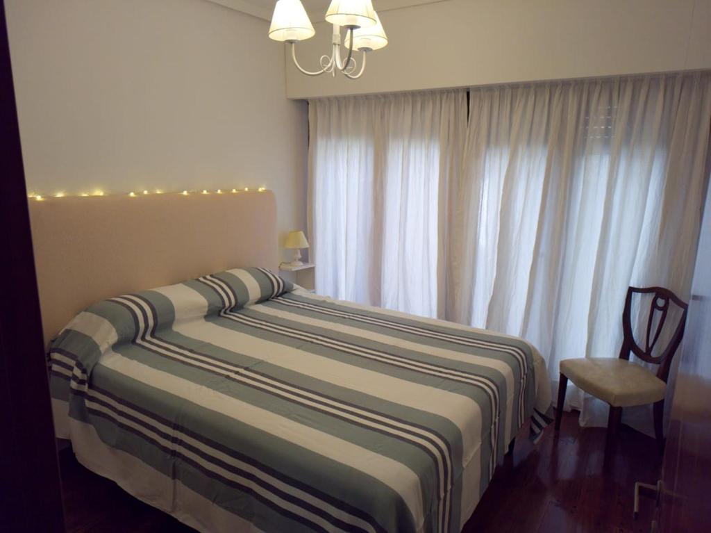 1 dormitorio con 1 cama con silla y ventana en Depto impecable en La Perla Mar del Plata en Mar del Plata