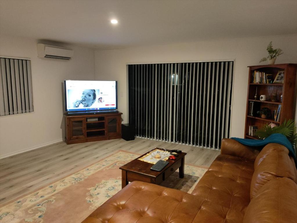 a living room with a couch and a flat screen tv at Harbourside Haven in Ohope Beach