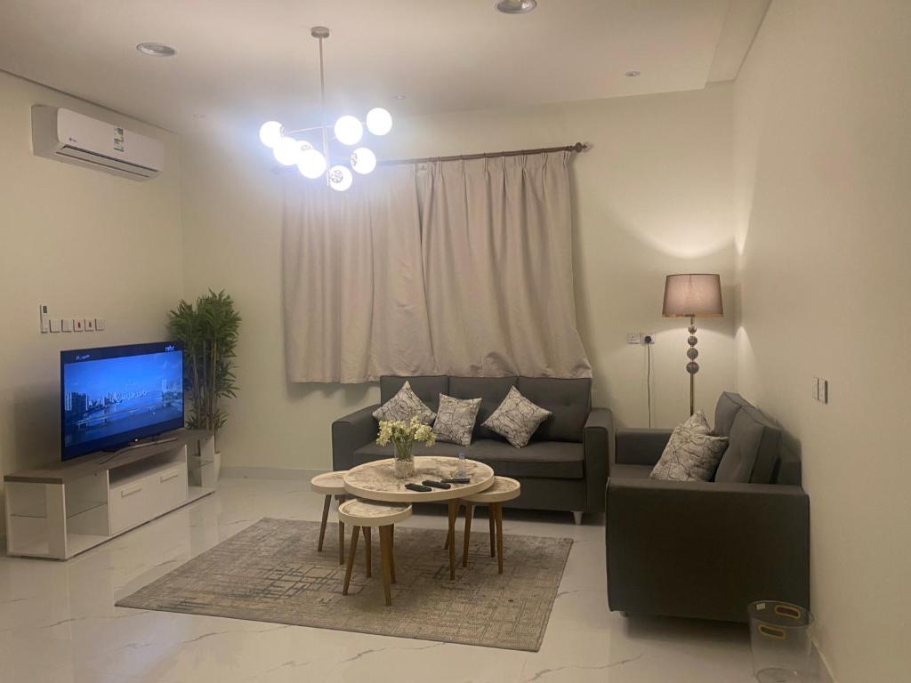 a living room with a couch and a table and a tv at غرفتين نوم صاه ومطبخ وسطع واسع in Unayzah