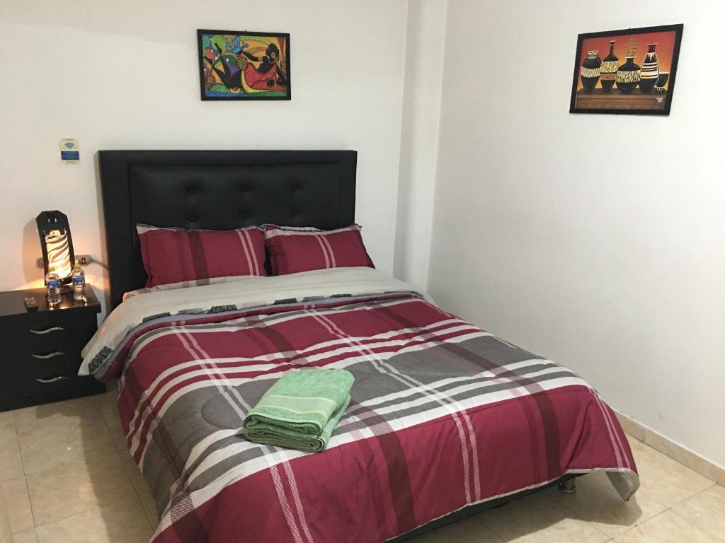 a bedroom with a bed with a red and white comforter at Dorado Airport rooms & apartments in Bogotá