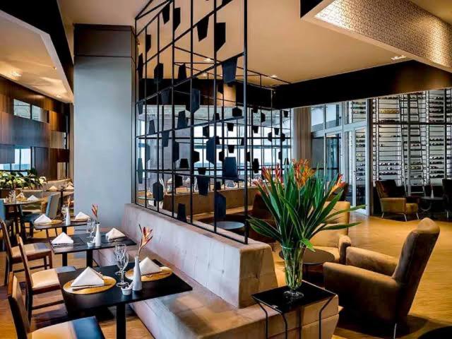 a restaurant with tables and chairs and a lobby at Sofisticado Flat Particular Grand Mercure in Brasilia