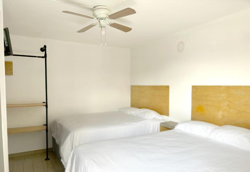 Cette chambre dispose de 2 lits et d'un ventilateur de plafond. dans l'établissement Edificio los Alcatraces, à Tijuana