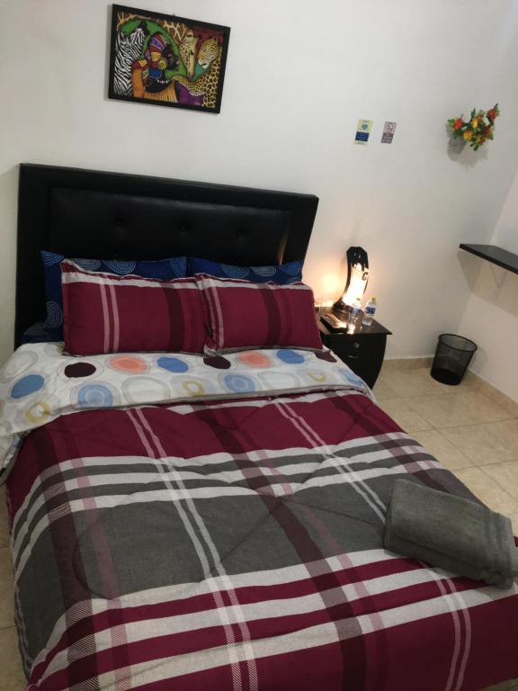 1 dormitorio con 1 cama con manta roja y blanca en Dorado Airport rooms & apartments, en Bogotá
