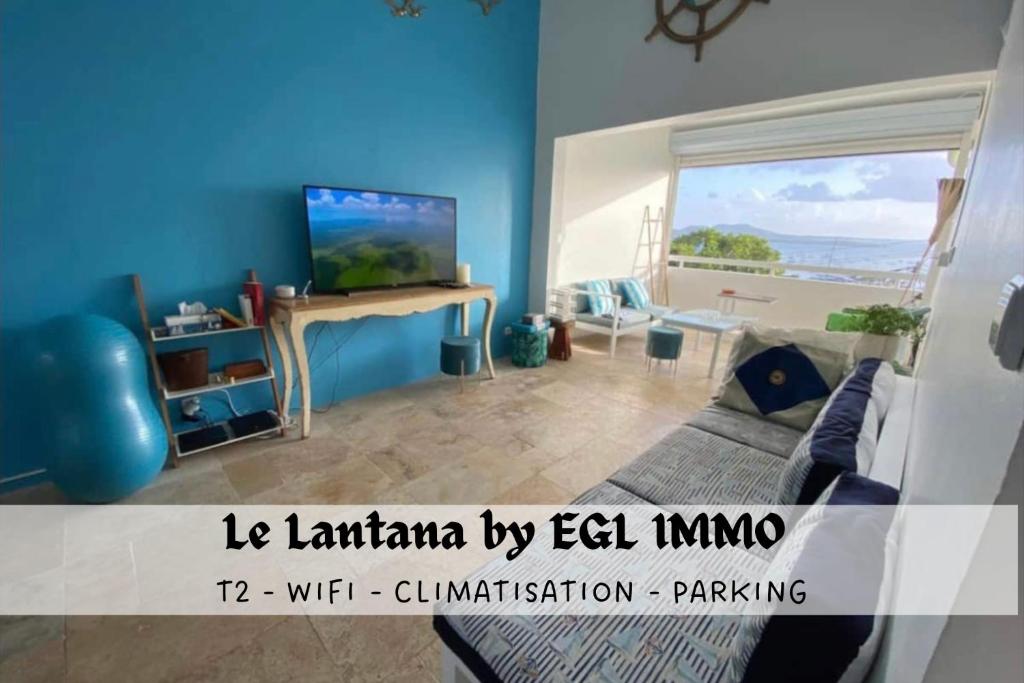 a living room with a couch and a television at Le Lantana by EGL IMMO in Le Marin