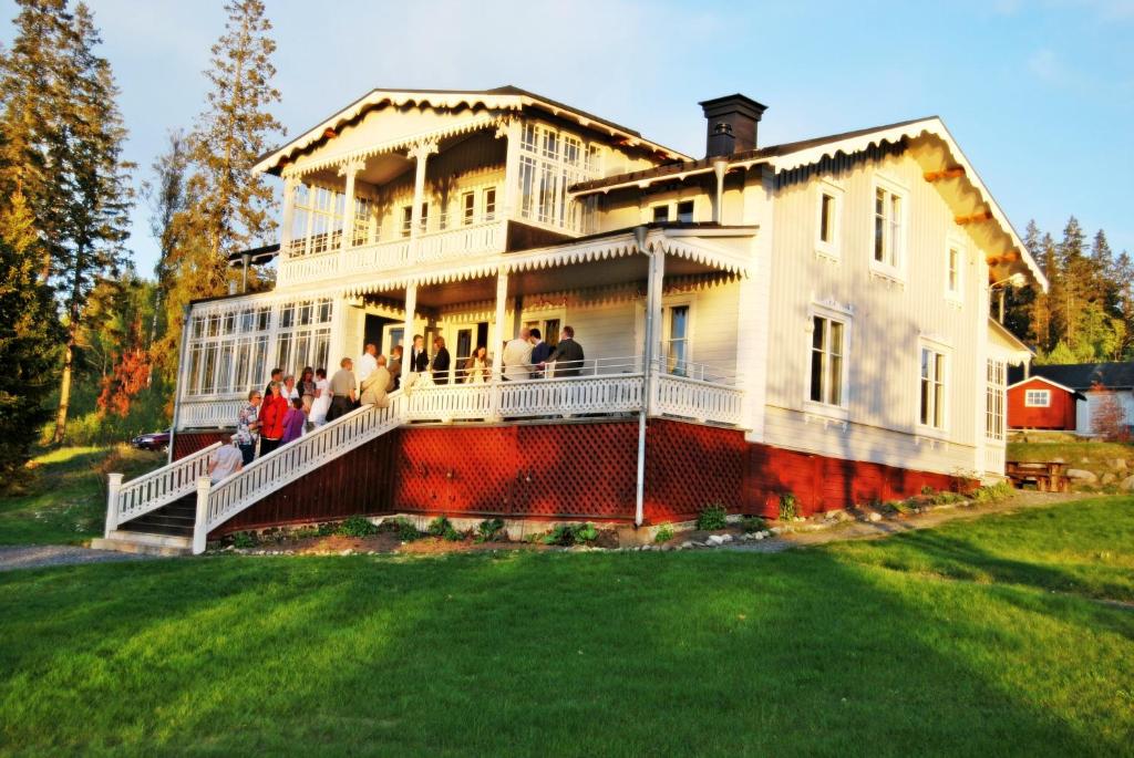 un groupe de personnes debout sur la terrasse couverte d'une grande maison dans l'établissement Villa Fridhem, Härnösand, à Härnösand