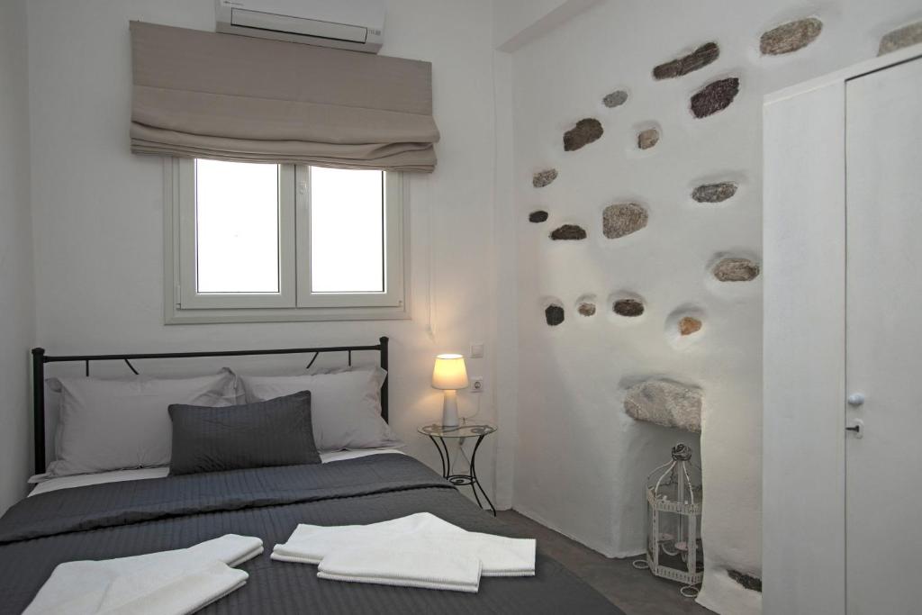 a bedroom with a bed and a window with rocks on the wall at Portes View House in Parikia