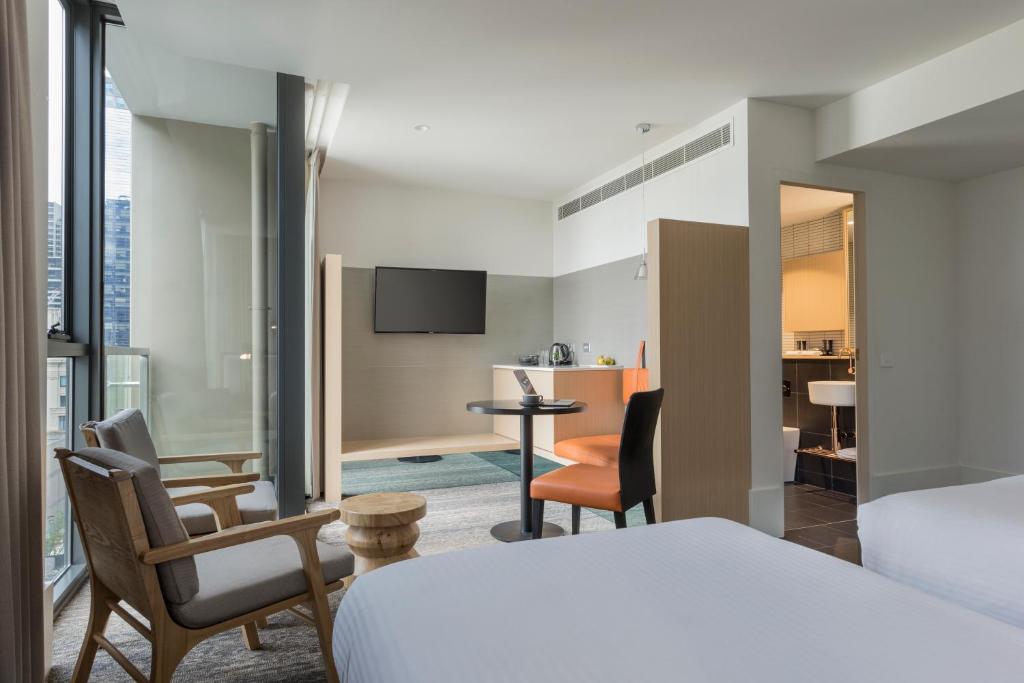 una camera d'albergo con letto e soggiorno di Brady Hotels Central Melbourne a Melbourne