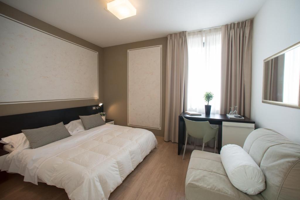 Habitación de hotel con 2 camas, escritorio y escritorio. en Berghotel, en Bérgamo