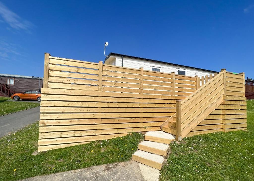 a wooden fence with steps in the grass at Shear Barn Holiday Park in Hastings