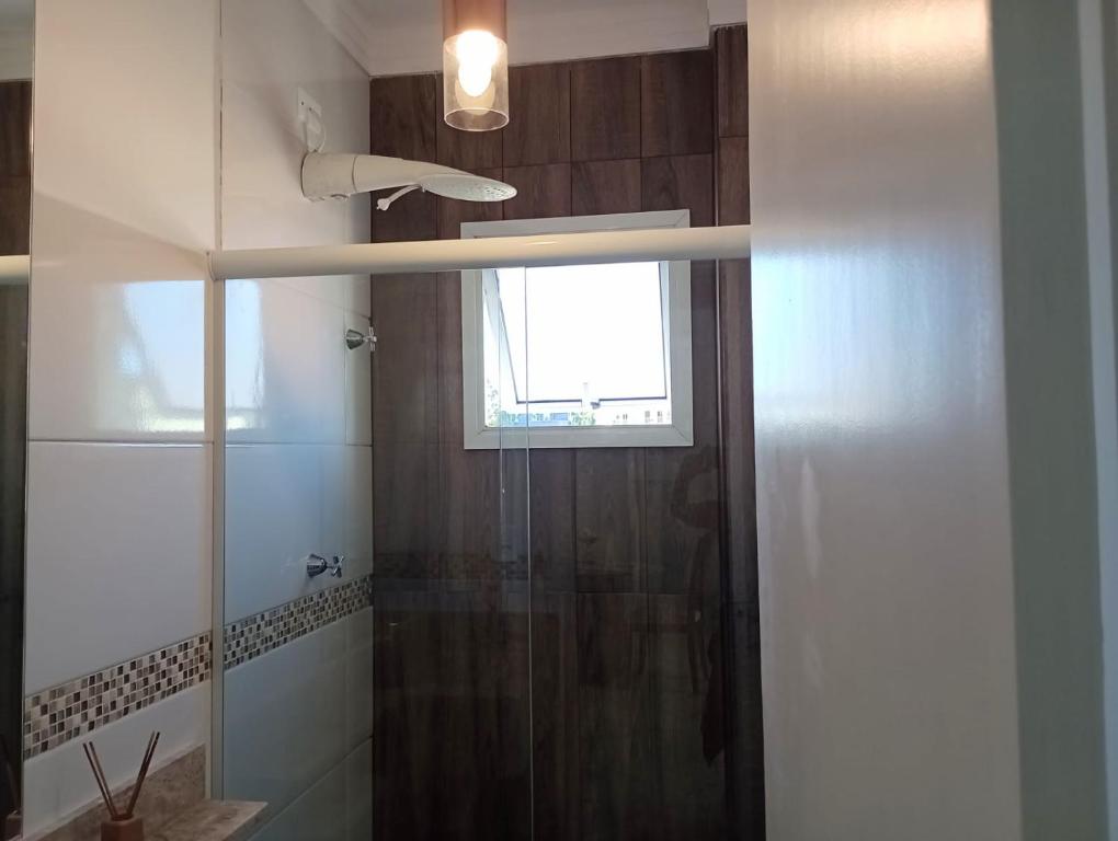 a bathroom with a glass shower with a window at Cantinho FW in Ubatuba