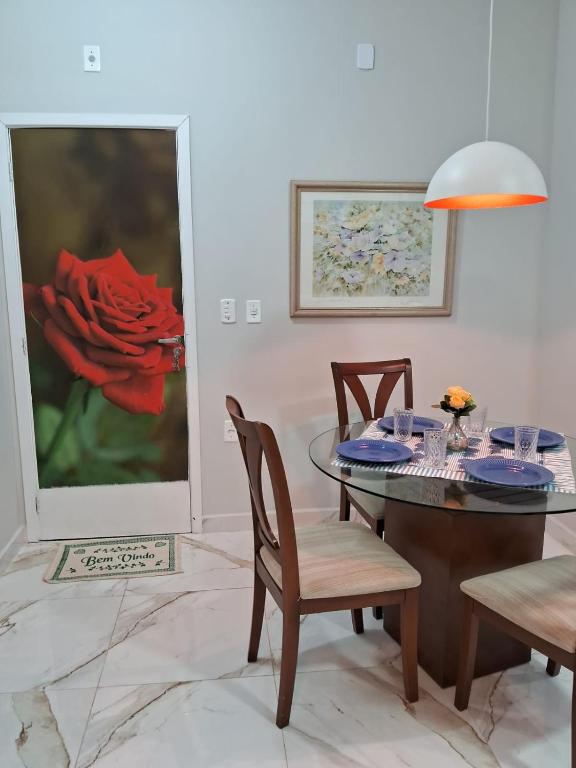 a dining room with a table and chairs and a red rose at Cantinho FW in Ubatuba