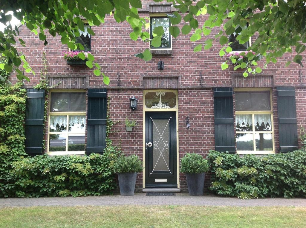 HeythuysenにあるHoeve Het Verre Einderのレンガ造りの家(黒いドア、窓付)