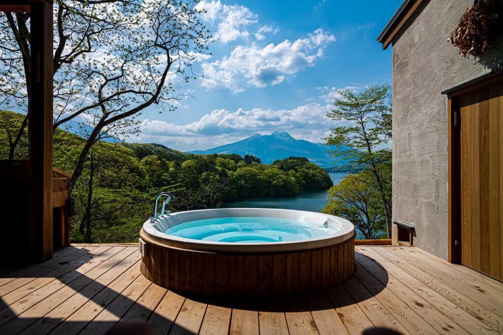 bañera de hidromasaje en una terraza con vistas a la montaña en 野尻湖の絶景を楽しむ、貸切サウナ付き一軒家 Anoie（あの家）, en Shinano
