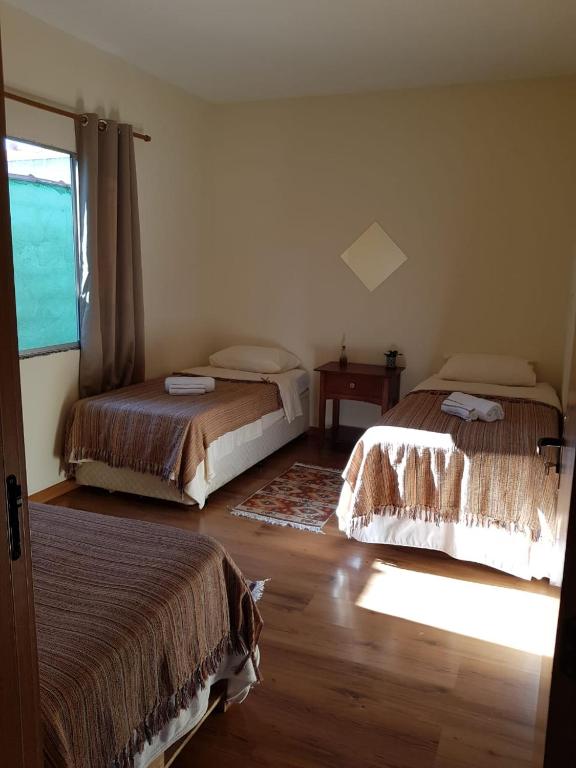 a bedroom with two beds and a window at Abrigo Serafina#cama&café in Itamonte