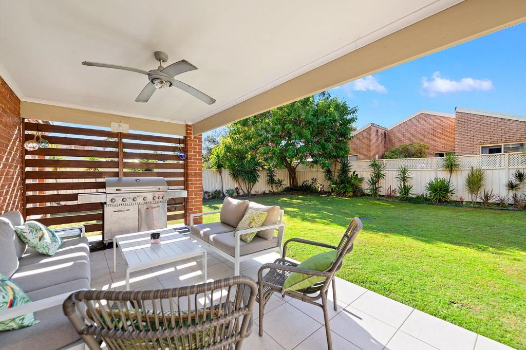 une terrasse avec un canapé, des chaises et un grill dans l'établissement Seabreeze at Shoal Bay, à Shoal Bay