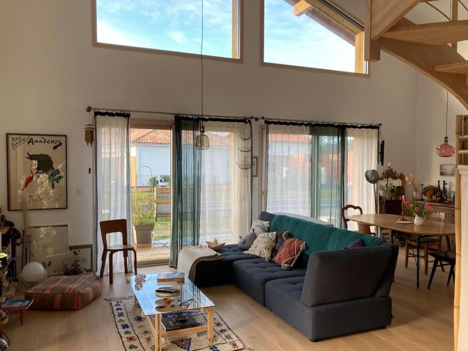 un salon avec un canapé bleu et une table dans l'établissement Belle villa neuve bioclimatique proche plages golf, à Seignosse